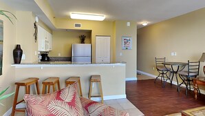 Un espacio habitable compacto con kitchenette, zona de comedor y sala de estar con sofá y sillas.