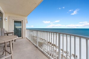 A balcony with a view of the beach and ocean.