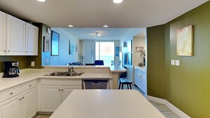 Une cuisine moderne avec des meubles blancs, un îlot central et une vue sur un balcon.