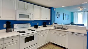A modern kitchen with white cabinets, a microwave, stove, and dishwasher. - Gulf Front Condo with Incredible Views and Resort Amenities (Panama City Beach)