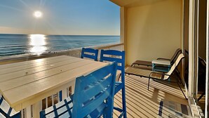 Ein Balkon mit Tisch und Stühlen mit Blick auf den Ozean.