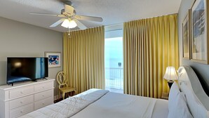 Ein Hotelzimmer mit Bett, Fernseher, Deckenventilator, Sessel und Blick ins Freie.