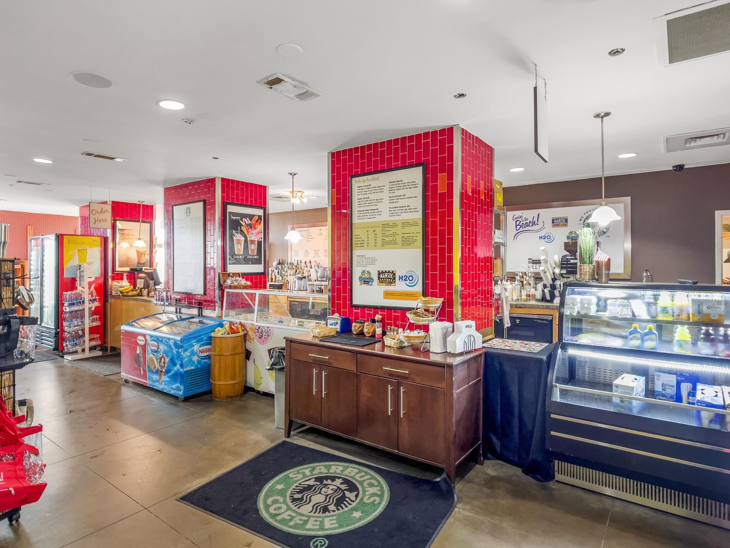 Interior de una cafetería Starbucks, con mostrador, menú y vitrina refrigerada.