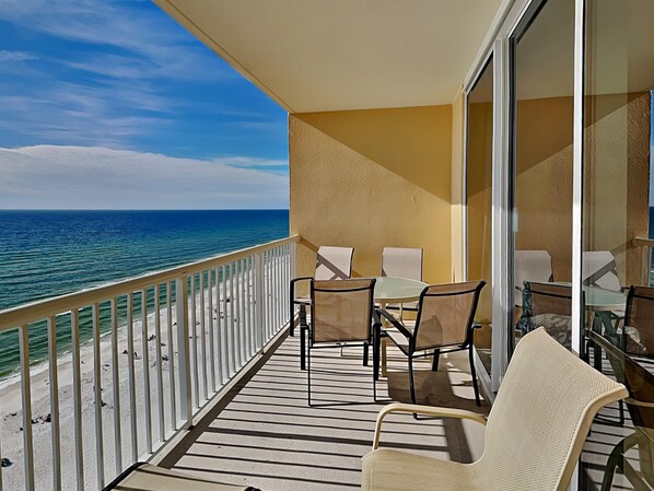 A balcony with a view of the ocean, featuring a table and chairs.