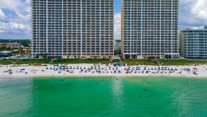 A beachfront hotel with multiple high-rise buildings, a sandy beach, and clear turquoise waters.