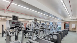 Une salle de sport équipée de tapis de course, de vélos elliptiques et d’appareils de musculation.