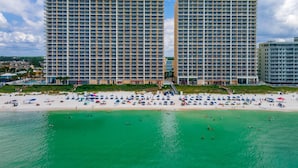 Un hôtel situé en bord de mer, composé de plusieurs immeubles de grande hauteur, avec une plage de sable fin et une eau turquoise cristalline.