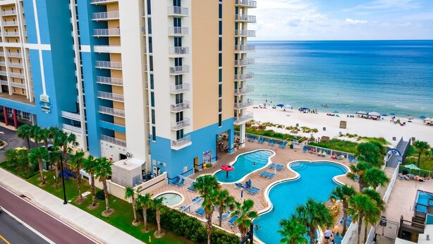 A high-rise hotel with a pool area, beach access, and a view of the ocean.