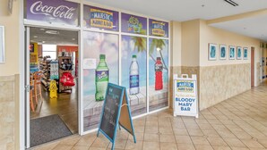 A store with a Coca-Cola sign, a Majestic Market & Bar, and a sign for the Bloody Mary Bar. - Majestic Beach Towers I #1703 | Gulf Front + Amenities (Panama City Beach)