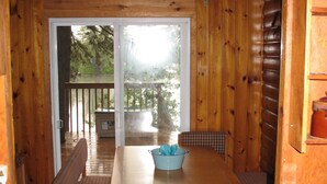 A wooden cabin with a dining table and four checkered chairs.
