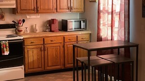 A kitchen with wooden cabinets, a microwave, a stove, and a table with stools. - Vacation Condo #5 2BR with full kitchen, walk to river and shops, pets welcome (Hardy)
