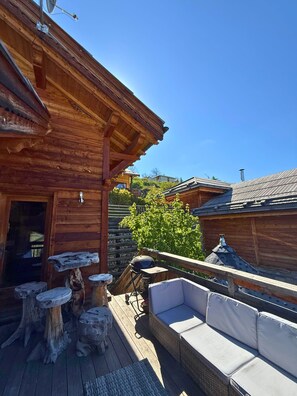 Une cabane en bois dotée d’une terrasse, de meubles de jardin et offrant une vue sur le paysage environnant.