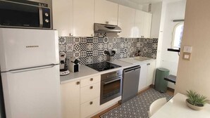 A modern kitchen with white cabinets, a built-in oven, a microwave, and a sink. - Apartment type T2 bis town center all on foot near beach (Cavalaire-sur-Mer)