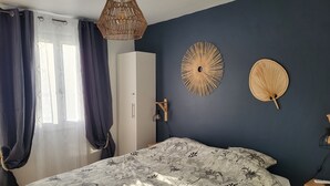A bedroom with a bed, a wardrobe, a hanging light fixture, and wall decor. - Apartment type T2 bis town center all on foot near beach (Cavalaire-sur-Mer)