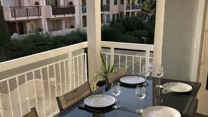 An outdoor dining area with a black table set for six, surrounded by wicker chairs. - Apartment type T2 bis town center all on foot near beach (Cavalaire-sur-Mer)