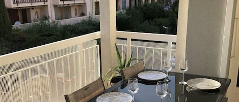 An outdoor dining area with a black table set for six, surrounded by wicker chairs.