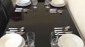A dining table set for four with white plates, glasses, and cutlery.