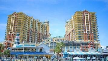 A marina with boats docked, surrounded by high-rise hotels with balconies and a clear sky.
