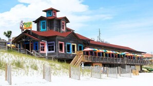 Un edificio in legno con tetto rosso e finestre colorate, situato su una spiaggia sabbiosa.
