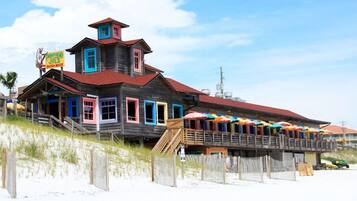 A wooden building with a red roof and colorful windows, located on a sandy beach.