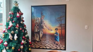Ein Essbereich mit Weihnachtsbaum, einem Gemälde und einem runden Holztisch mit Stühlen.
