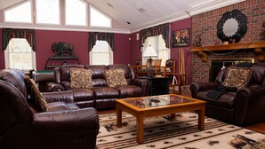 A living room with leather sofas, a glass coffee table, and a fireplace. - Farmhouse on Beautiful Bison Farm (Opelika)