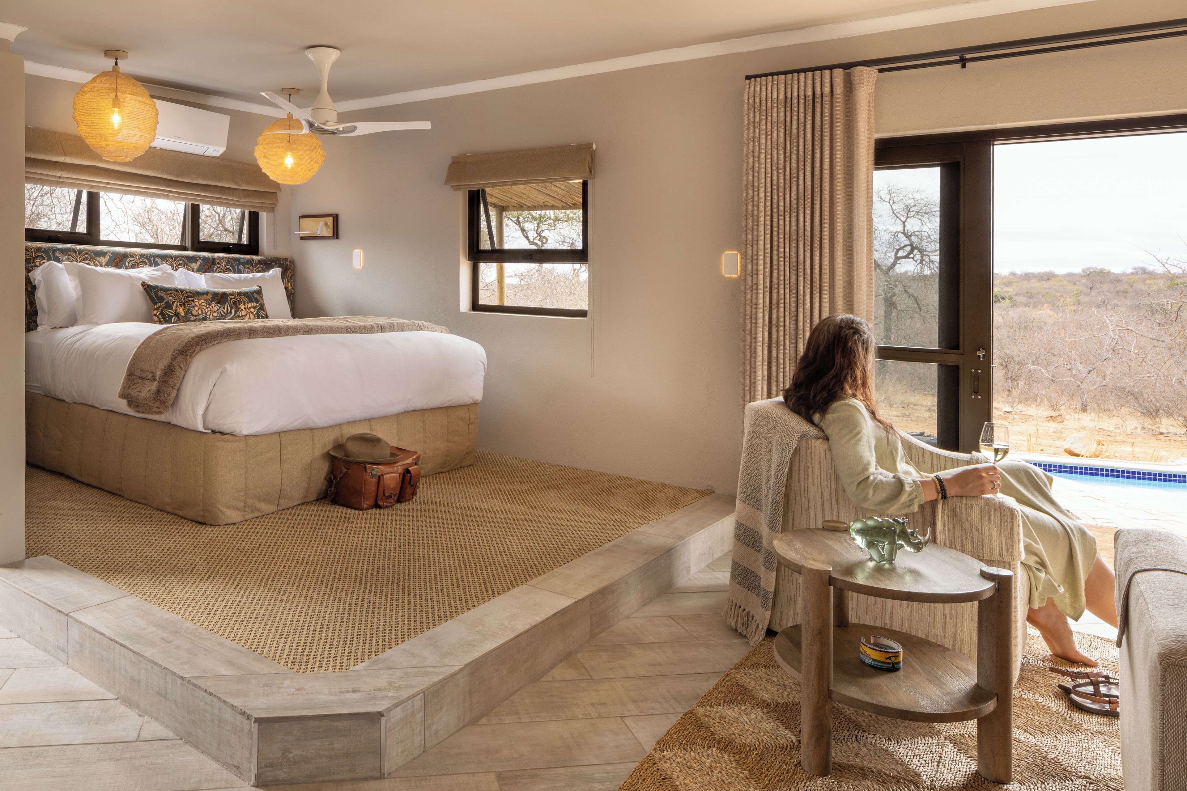 A bedroom with a large bed, a small table, and a view of the outdoors.