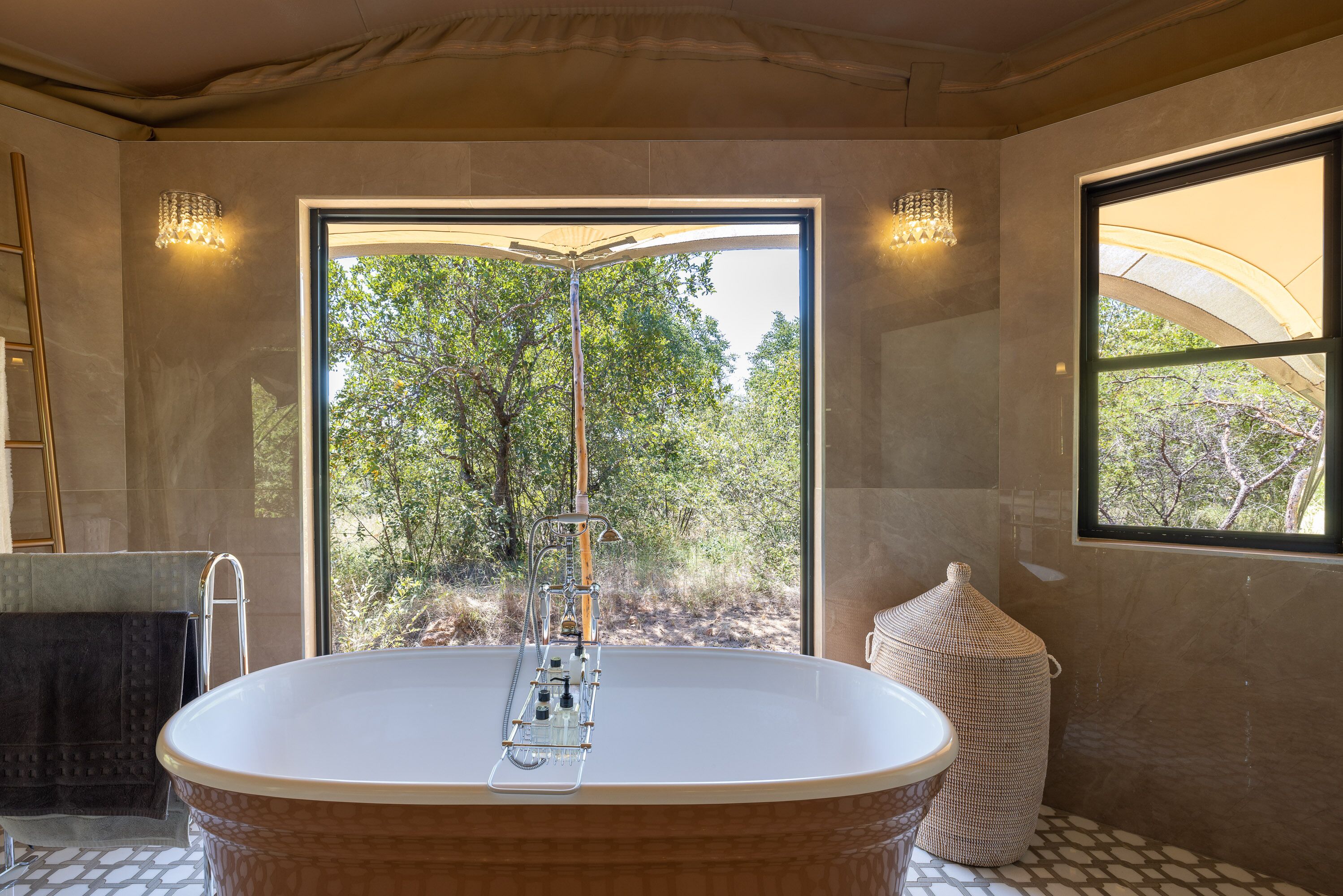 A modern bathroom with a freestanding bathtub, a large window, and a view of trees.