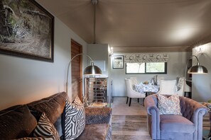 A living room with a brown leather sofa, a grey armchair, and a dining area with a table and chairs.