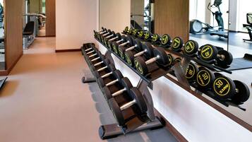 Un gimnasio con filas de mancuernas y equipamiento de ejercicio.