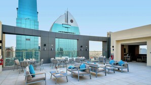 A rooftop lounge with outdoor seating and a view of a modern building. - Comfort Hotel Riyadh Olaya (Riyadh)