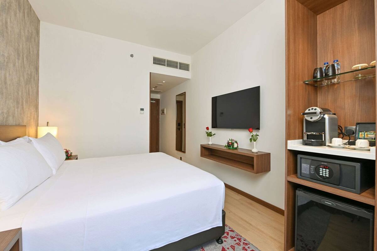 Une chambre d’hôtel équipée d’un lit, d’un téléviseur fixé au mur, d’une machine à café et d’un mini-réfrigérateur.