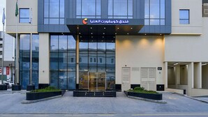 A modern building with a glass entrance, a sign with Arabic text, and a flagpole with flags. - Comfort Hotel Riyadh Olaya (Riyadh)