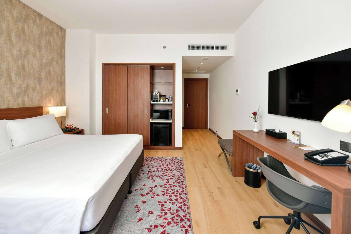 Une chambre d’hôtel équipée d’un lit, d’un bureau, d’une chaise, d’une télévision et d’une armoire.