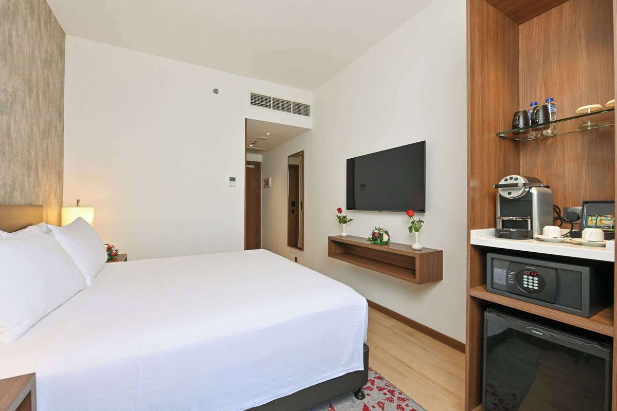 Une chambre d’hôtel équipée d’un lit, d’un téléviseur fixé au mur, d’une machine à café et d’un four à micro-ondes.