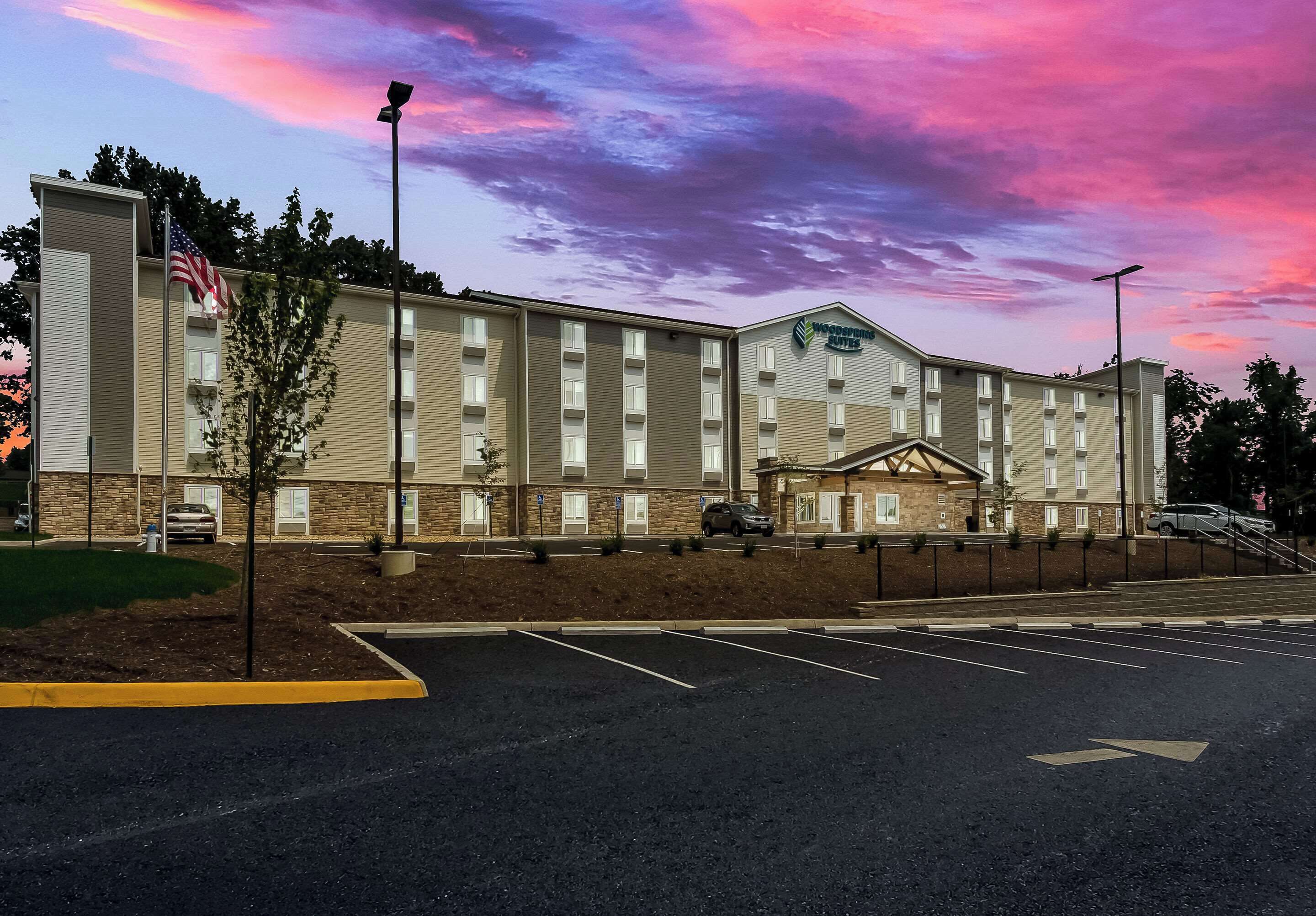 A hotel with a brick facade, multiple windows, and a parking lot.