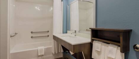A modern bathroom with a glass shower enclosure, a white sink, a dark wooden vanity, and a mirror above the sink.
