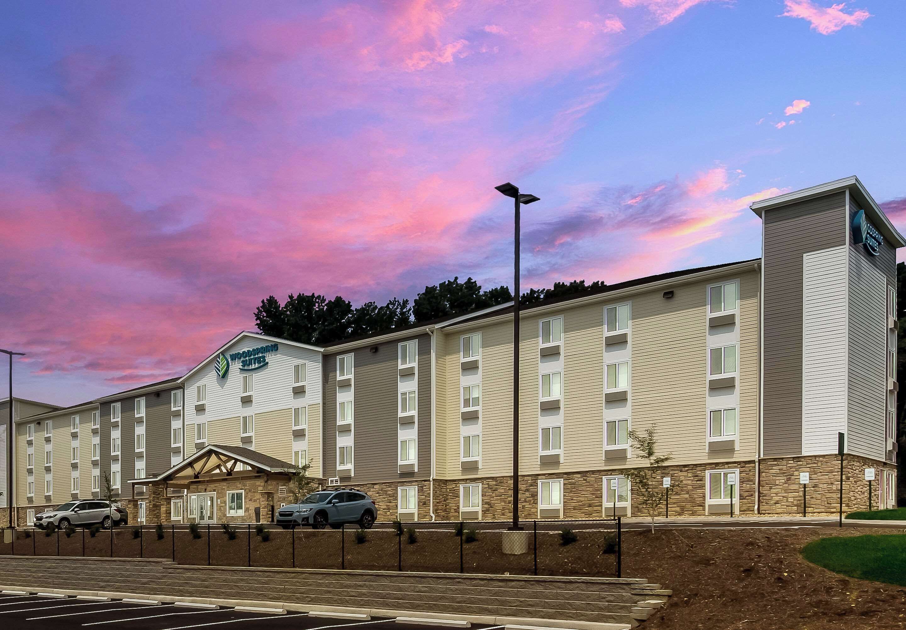 A hotel with a flat roof, multiple windows, and a parking lot.