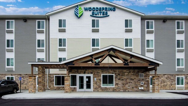 Ein mehrstöckiges Hotel mit einem gut sichtbaren Schild mit dem Schriftzug "Woodspring Suites".