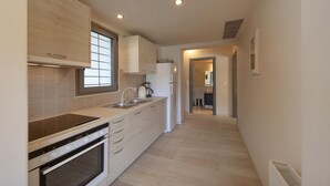 A modern kitchen with a built-in oven, a sink, and a window. - Crystal View Villa by Unique Villas Collection (Corinth)