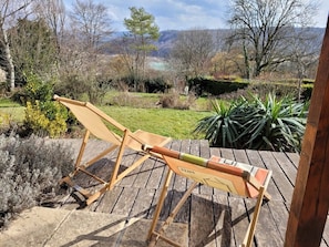Une terrasse en bois avec deux chaises et une table, également en bois.