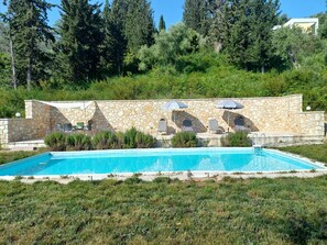 Ein Schwimmbecken mit Steinwänden und Liegestühlen.