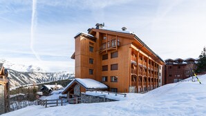 A multi-story wooden building with balconies, set against a snowy mountainous backdrop. - Courchevel 1850, elegant, 3 bedrooms, 92sqm, ski in ski out, exceptional view (Courchevel)