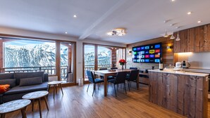 A modern kitchen with a wooden island, a dining area with a table and chairs, and large windows offering a mountain view. - Courchevel 1850, elegant, 3 bedrooms, 92sqm, ski in ski out, exceptional view (Courchevel)