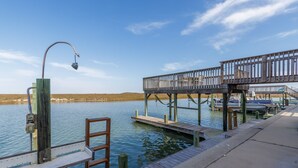Une jetée en bois s’étendant sur une étendue d’eau calme, avec une rambarde en métal et un lampadaire.