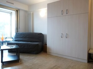 A compact room with a grey sofa, a small table, and a large wardrobe.