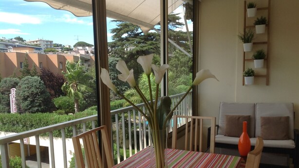 A balcony with a striped tablecloth, chairs, a vase with flowers, and a sofa with cushions. - Spacious studio in the center of Cannes, nice terrace, easy walk to the Croisette and Palais - 1923 (Cannes)