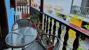 A balcony with two wicker chairs and a small table, overlooking a street with traditional buildings and a clear sky. - Casa Art Gallery, Cartagena Historic Center (Cartagena de Indias)