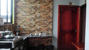 A kitchen with a stone backsplash, a gas stove, and various kitchen items on the counter. - macas center (Macas)