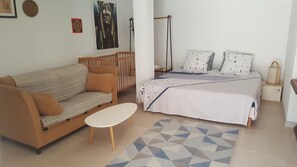 A bedroom with a bed, a sofa, a small table, and a crib. - Large studio in a Provençal house (Cagnes-sur-Mer)